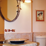 Cory Powder Room - These clients wanted a unique look for the powder room of their new home. A broken edge piece of travertine and floating bowl sink over a wooden pedestal make a dramatic design statement. The wall-mounted faucet, iron mirror, and wall sconces complete the design.
