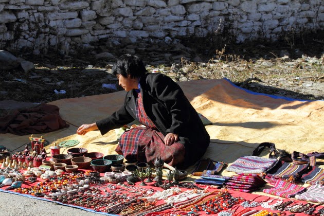 Street hawker selling her wares in front of Jampey Lakhang, Bumthang