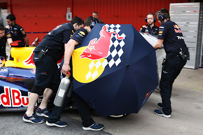 механики Red Bull зарывают болид Себастьяна Феттеля зонтиками от фотографов на предсезонных тестах 2012 в Барселоне 4 марта 2012