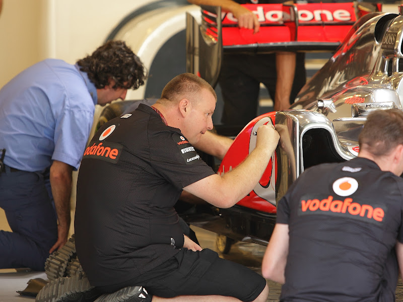 механик McLaren рисует на болиде Льюиса на Гран-при Абу-Даби 2011