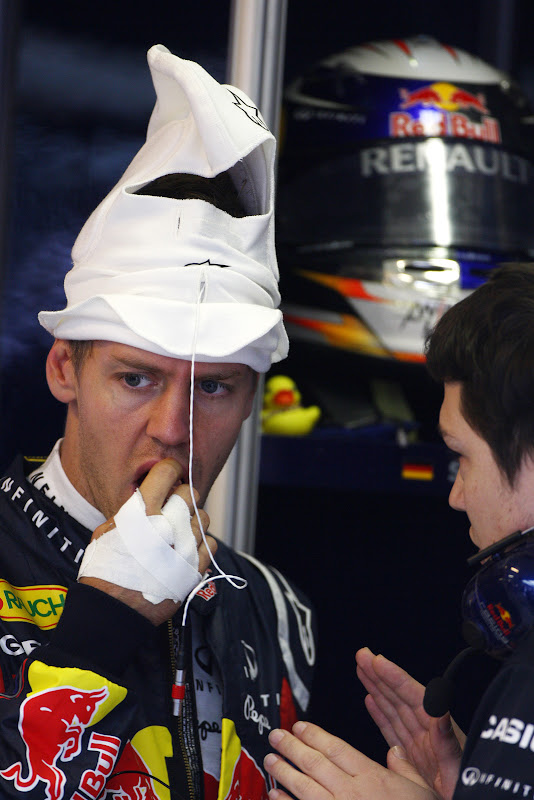 Себастьян Феттель с подшлемником на голове слушает инженера на Гран-при Венгрии 2011