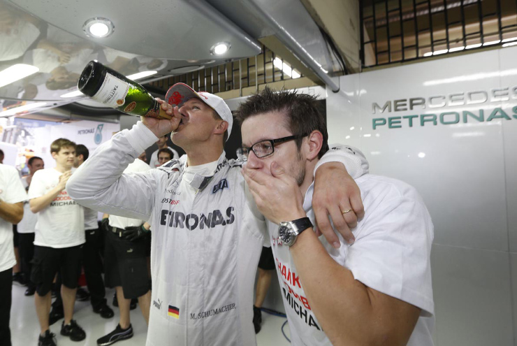 Михаэль Шумахер выпивает шампанское с механиком Mercedes на Гран-при Бразилии 2012