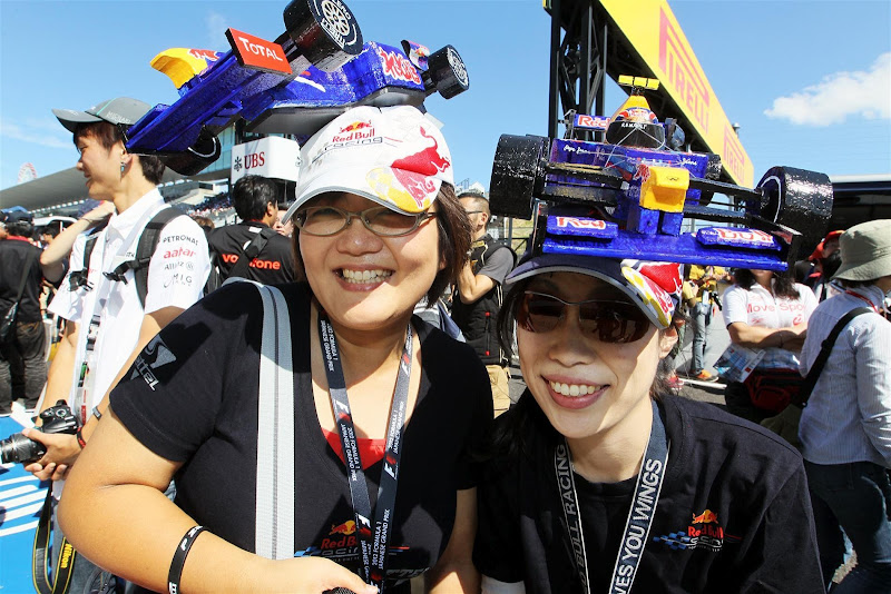 болельщицы Марка Уэббера и Себастьяна Феттеля с болидами Red Bull на кепках на Гран-при Японии 2012
