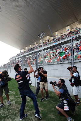 Марк Уэббер кидает индийский флаг в болельщиков на параде пилотов Гран-при Индии 2011