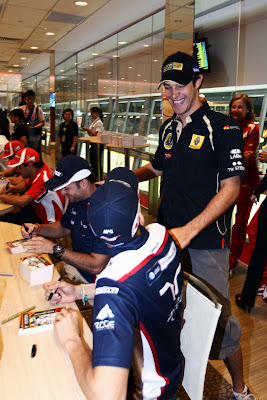 Бруно Сенна подходит к столику Пастора Мальдонадо и Рубенса Баррикелло на автограф-сессии Гран-при Сингапура 2011