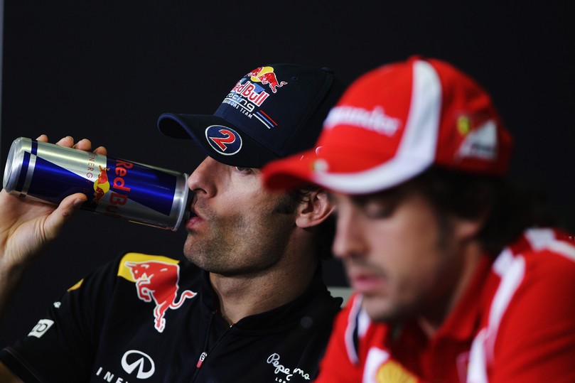Марк Уэббер пьет из банки Red Bull на фоне Фернандо Алонсо на пресс-конференции в четверг на Гран-при Испании 2011