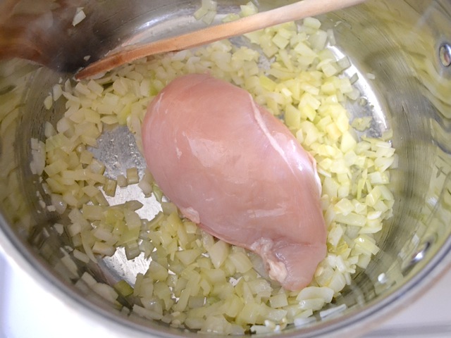 raw chicken breast added to pot 