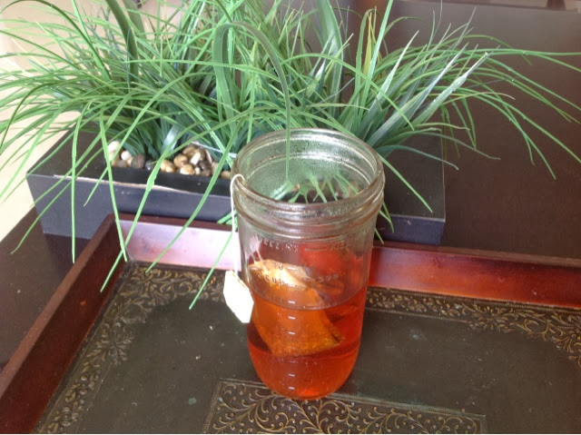 Mason jar of orange colored tea with tea bag
