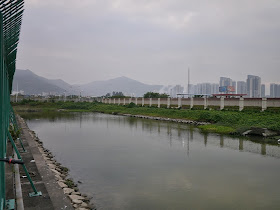 a strip of water with mountain and apartment complexes in the background