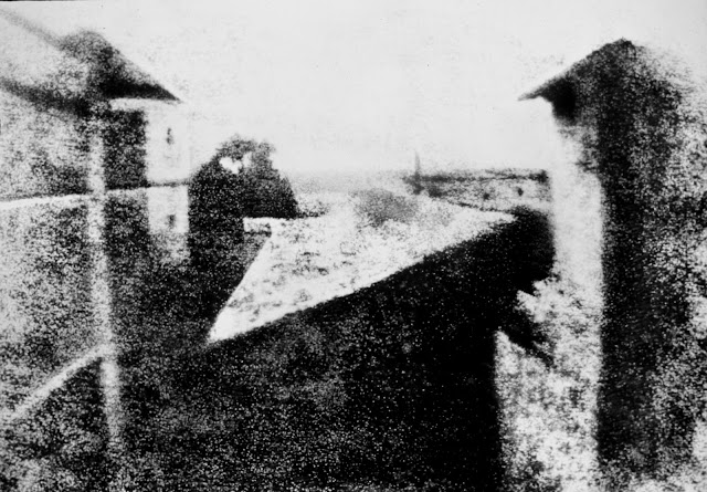 View from the Window at Le Gras, the first successful permanent photograph created by Nicéphore Niépce in 1825, Saint-Loup-de-Varennes. Captured on 20 × 25 cm oil-treated bitumen. Due to the 8-hour exposure, the buildings are illuminated by the sun from both right and left.