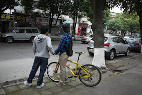 two young men stranding next to a bicycle in Zhuhai, China