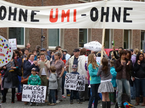 Protest vor dem Kölner Rathaus mit Plakaten und Transparent: »Ohne ÜMI…«.