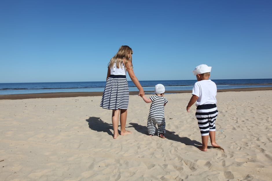 Young girl and two baby brothers playing on a beach