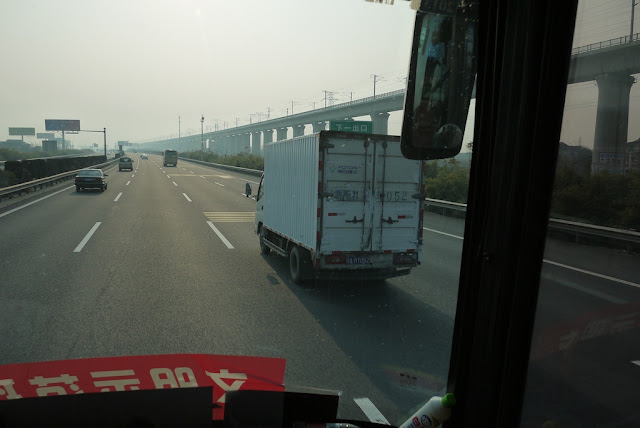 view of road and nearby high speed rail tracks from a bus in China