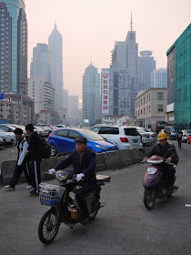 two men on motorbikes and two boys walking on Pudong Avenue in Shanghai