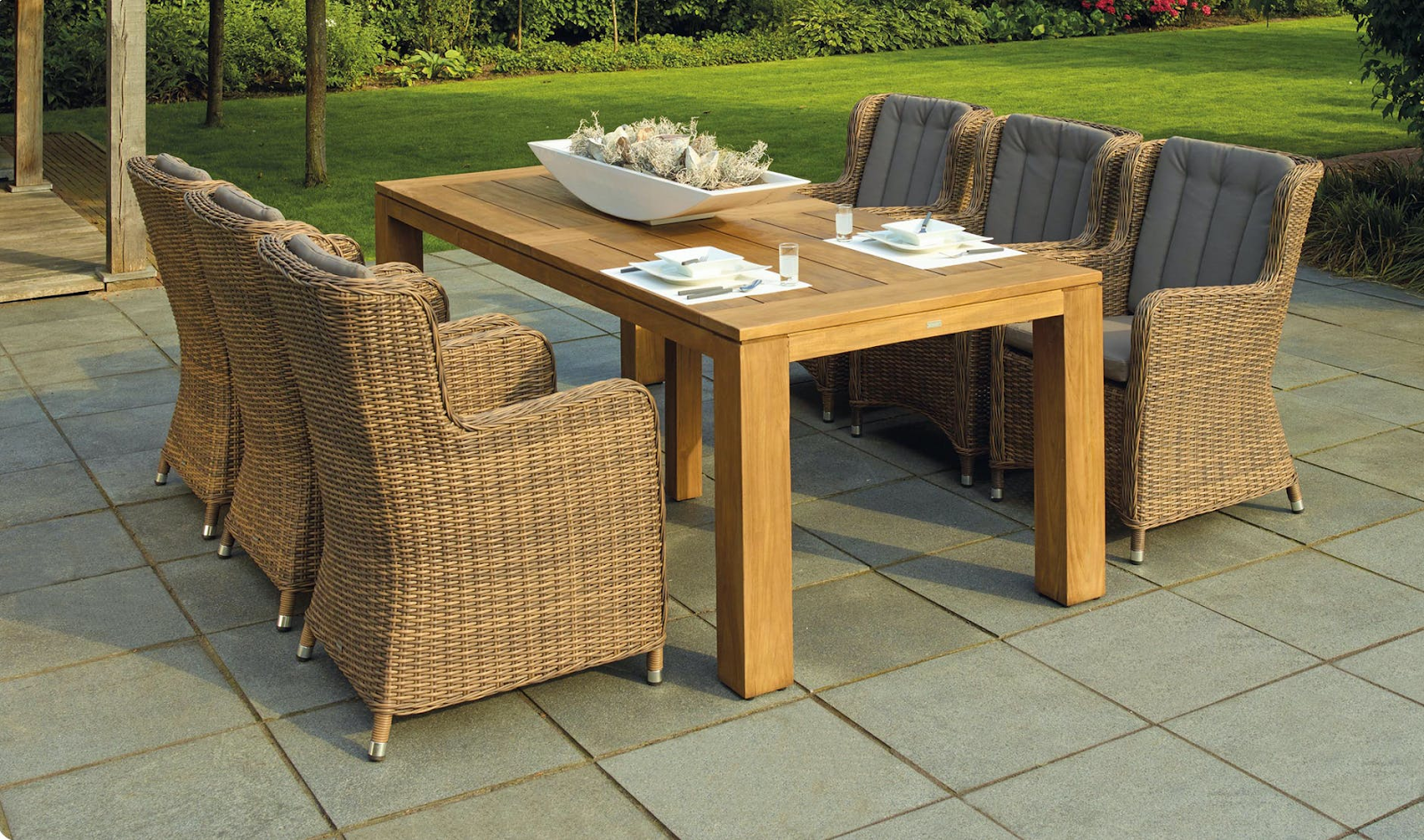 Garden seating area with wooden table and wicker chairs
