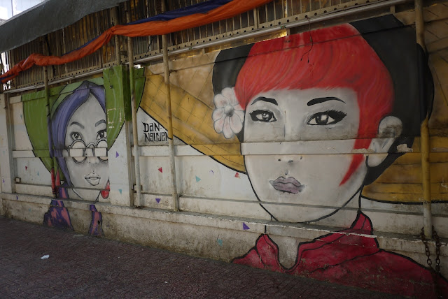 colorful paintings of the faces of two women on a wall in Ho Chi Minh City