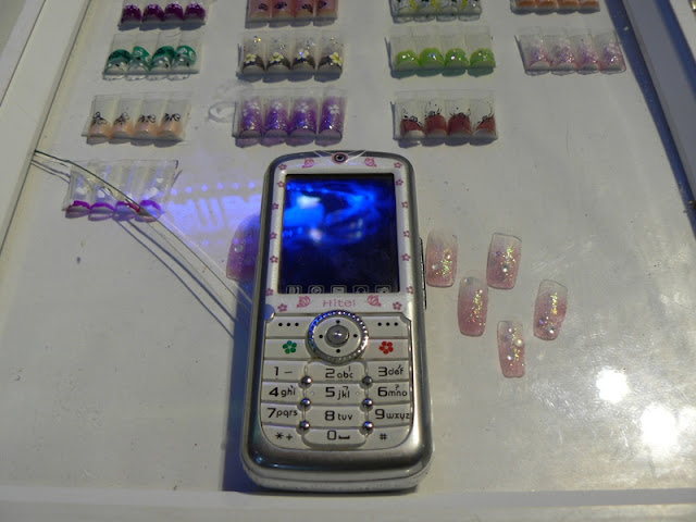 Hitel mobile phone on top of a display case of fake nails in China