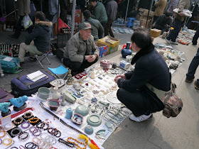 seller wearing a Chinese People's Liberation Army "Mao" cap at an outdoor antique market in Changsha, China