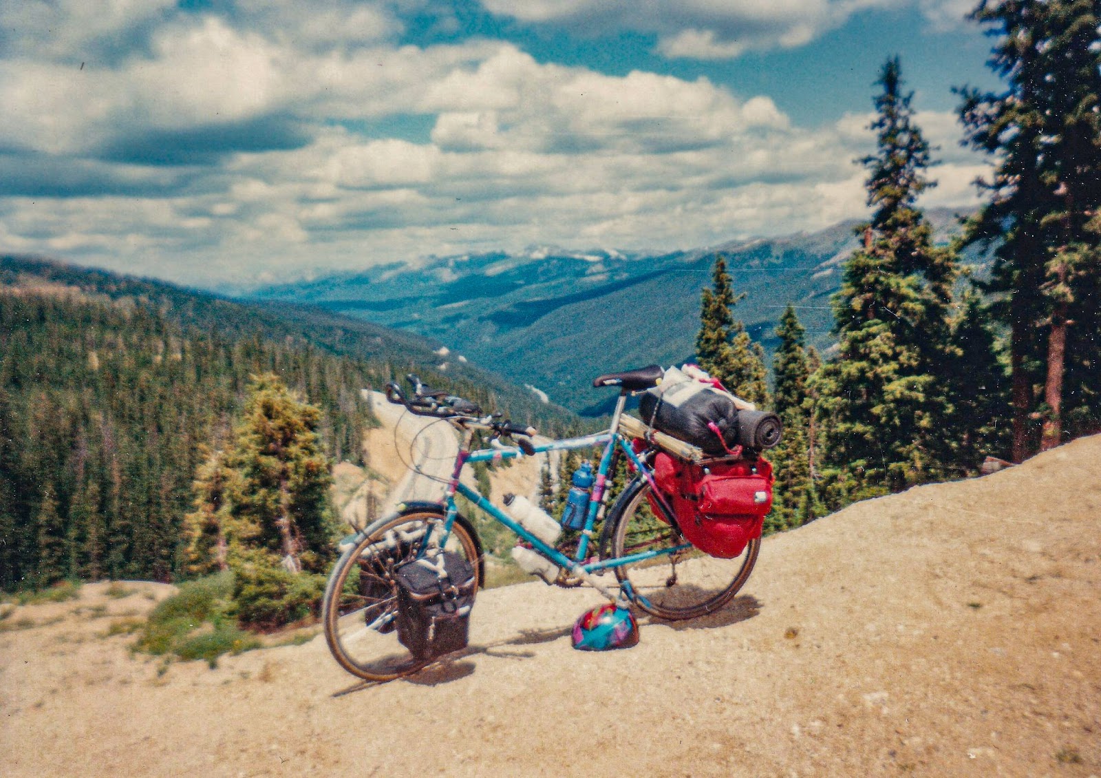 A bike is propped up in front of a distant mountain valley. 