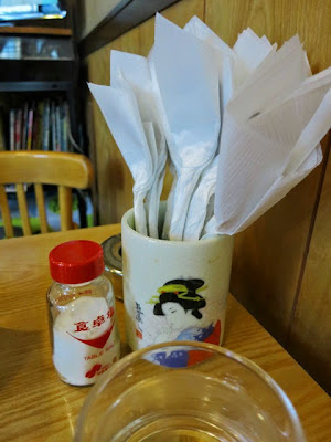 卓上に置かれたナフキンで包まれたスプーンと卓上塩