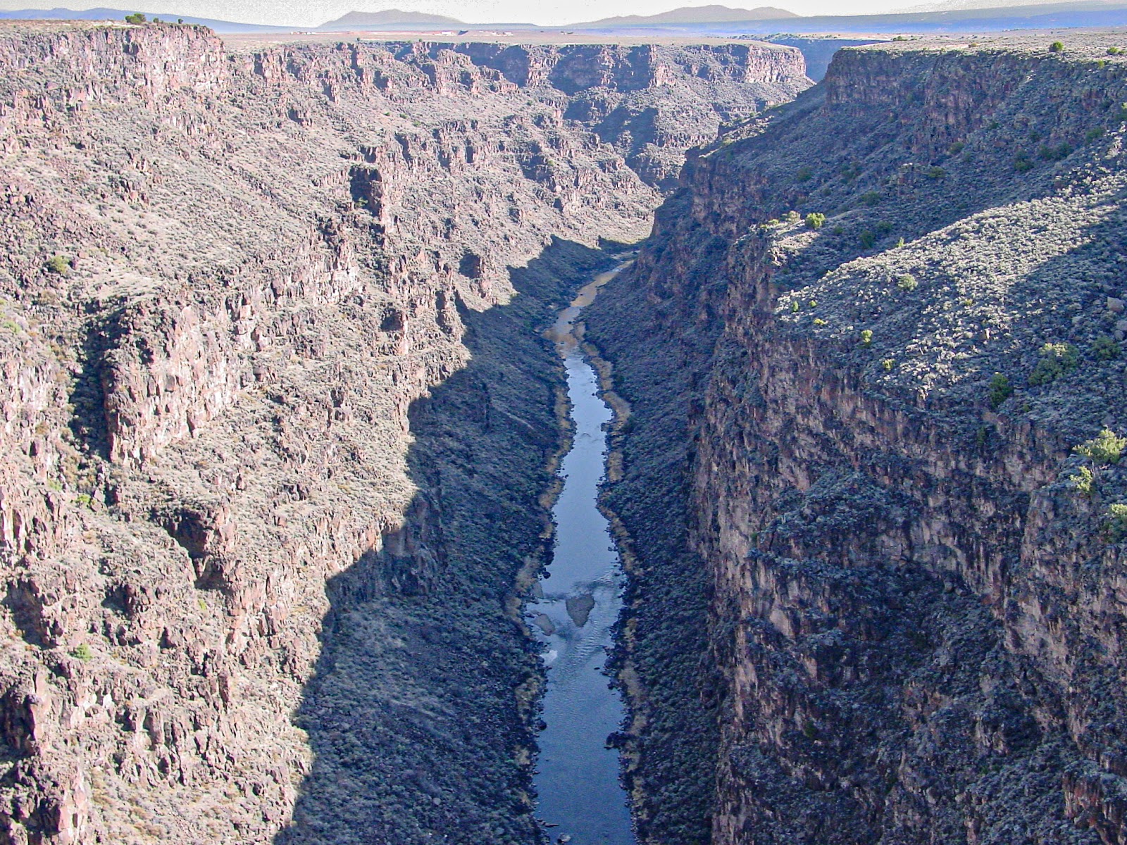 A river flows hundreds of feet below the rim of a steep gorge. 