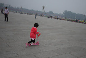 little girl riding a pink kick scooter at Tiananmen Square