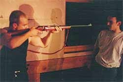 photo of a scene, image of Joseph Williams as Mickey pointing a rifle at Dean, played by Juan Modinger