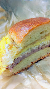 Portland Penny Diner's breakfast sandwich of PDXWT duck bologna, sauerkraut, coffee mayo, egg, american cheese, on the soft, buttery, and fresh parker house roll.