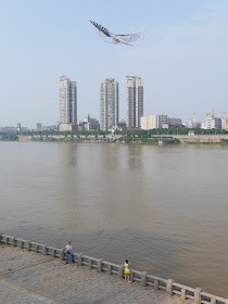 man flying a bird kite next to the Xiang River in Hengyang