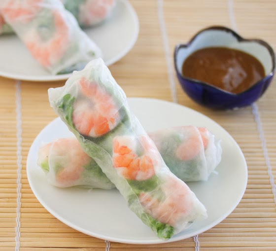 photo of two spring rolls on a plate with dipping sauce in the background