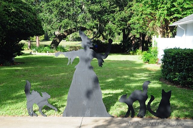 Front view of a witch cutout with three black cats. 