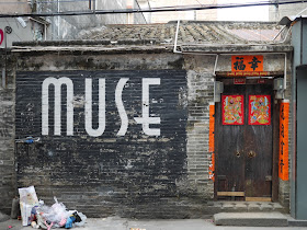 the word "MUSE" written in a large modern script on an old Chinese style building with traditiona; style decorations around its door