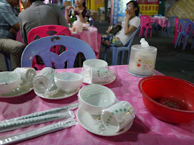 plastic wrapped table setting on an outdoor table with a young woman smoking in the background in Zhuhai, China
