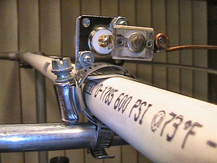 Close
                      up view of the feed point - SO-239 receptacle and
                      center point of halo loop are secured to the boom
                      with hose clamps. An Arco 466 mica compression
                      trimmer capacitor 105-480 pF is soldered between
                      the center pin of the SO-239 and the gamma match
                      rod.