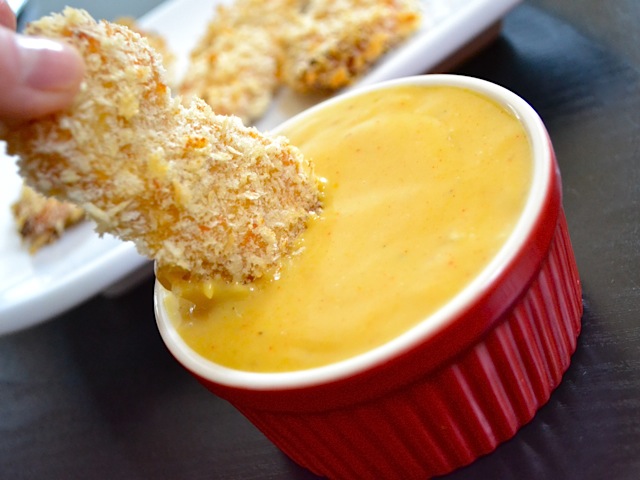 Close up of honey mustard chicken strip being dipped into sauce 