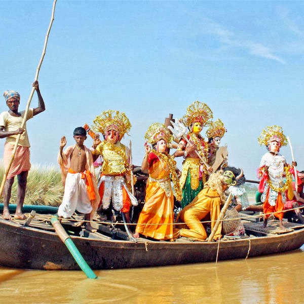 Artists dressed like Goddess Durga travel by a boat across Ajoy River in Birbhum on Wednesday during Durga puja festival.