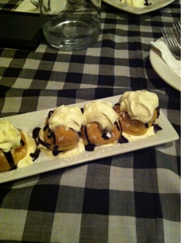 A plate of profiteroles on a black-and-white checked tablecloth.
