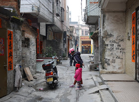 woman and little girl looking at a motorbike in an alley in Yangjiang, China