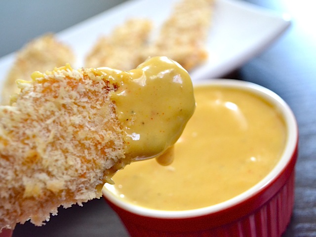 Close up of honey mustard chicken strip drenched in sauce after being dipped 