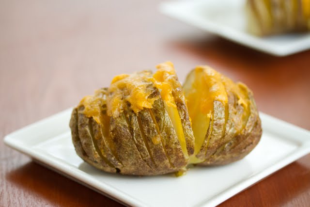 close-up shot of a hasselback potato on a white plate.