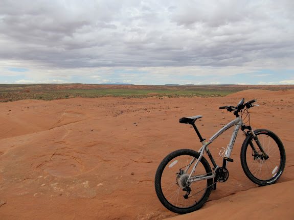 Slickrock with Saucer Basin looking unusually green in the distance title=