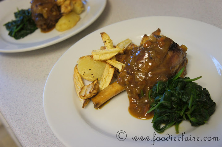 spiced lamb shanks slow cooked served with roast potatoes parsnip and spinach