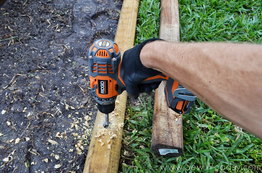 Hand holding an orange Ridgid drill. 