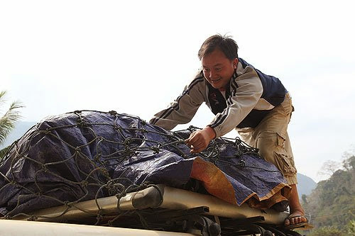 Laotian Driver secures luggage on roof of bus, taking the bus in Laos, luggage on a Laotian bus