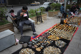 man eating lunch while selling small stones outside Tianxinge Antique City in Changsha, China