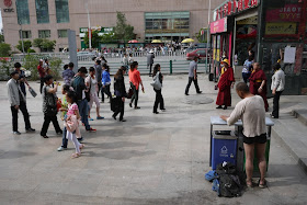 people walking on sidewalk and man standing in his underwear in Xining, Qinghai, China