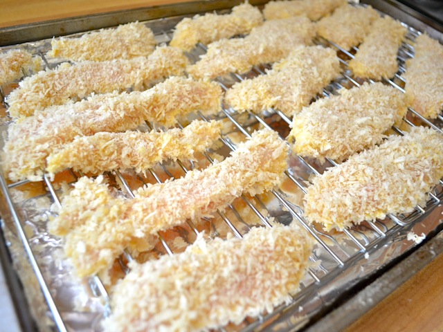 breaded chicken strips laid on pan ready to bake 