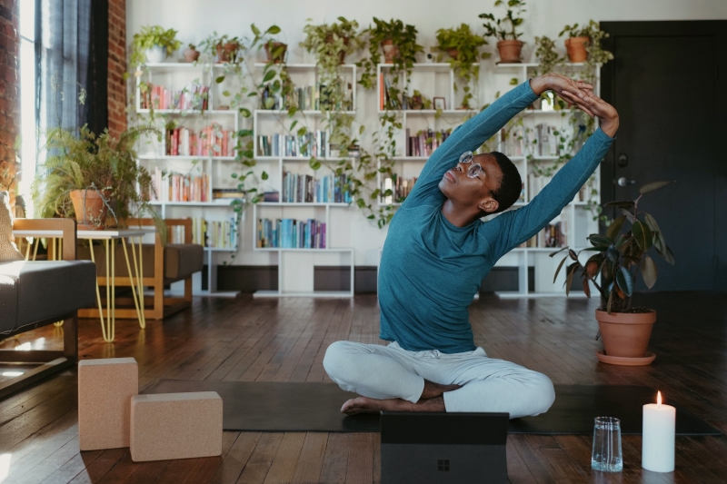 a young man doing a side stretch on a yoga mat in a living room