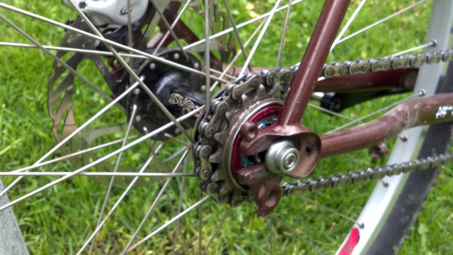 Right side, close up view of a black Surly Ultra New bike hub, installed in the rear wheel of a brown bike - on grass 